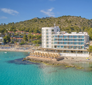 Modernes Strandhotel mit direktem Zugang zum t&uuml;rkisblauen Meer und Sonnenschirmen am Sandstrand.