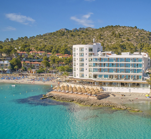 Modernes Strandhotel mit direktem Zugang zum t&uuml;rkisblauen Meer und Sonnenschirmen am Sandstrand.