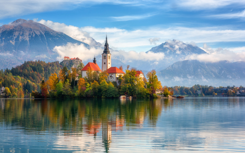 Ber&uuml;hmter Bleder See in Slowenien, atemberaubende Herbstlandschaft. Malerischer Blick auf den See, Insel mit Kirche, Burg Bled, Berge und blauer Himmel mit Wolken,